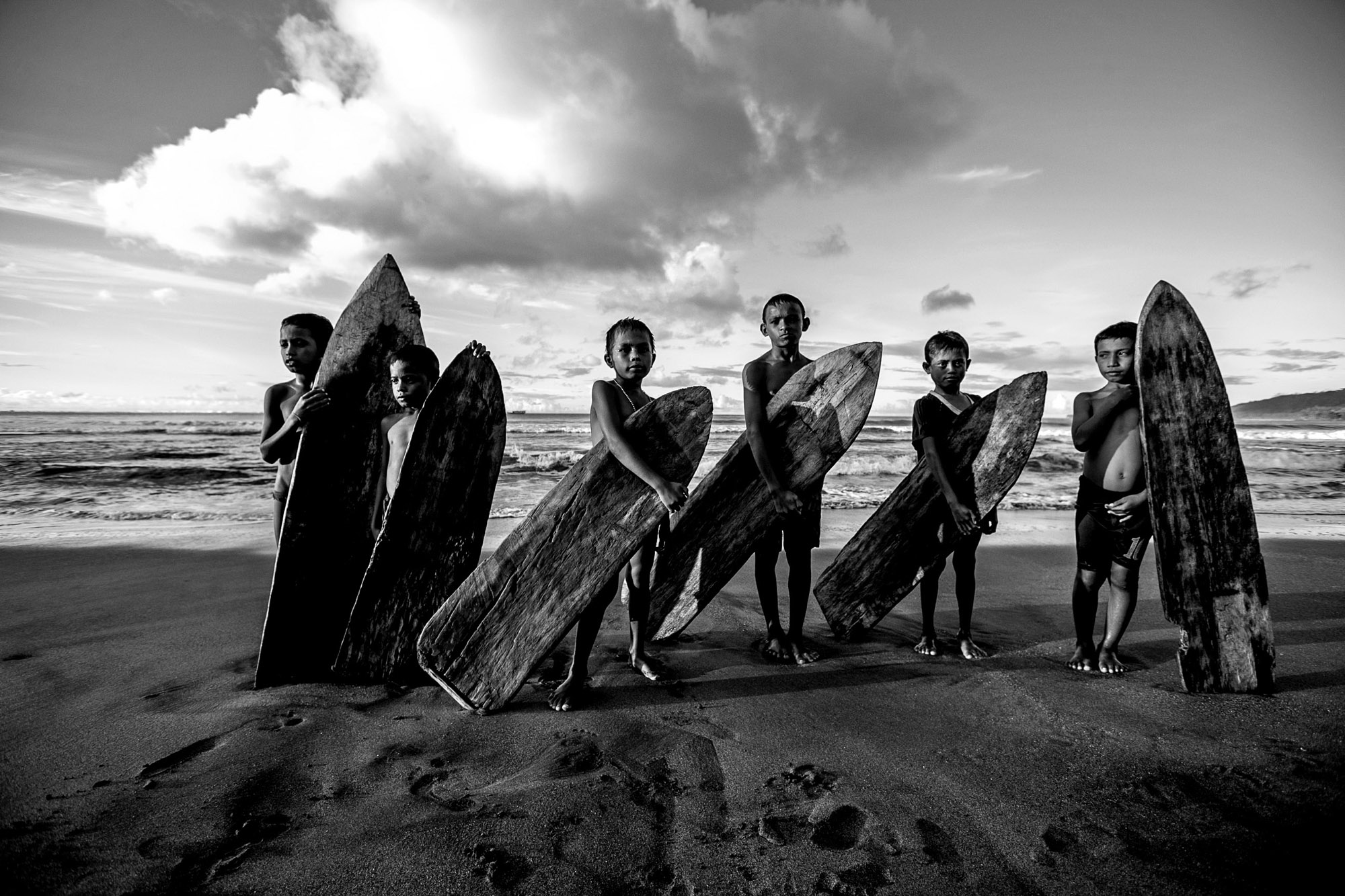 February 2014 Local kids surfing wooden boards-Searching for waves in the Pacific Ocean, Northern Indonesia with Indonesian surfers Marlon Gerber and Mega Semadhi aboard the Pulse surf charter boat. Photo Jason Childs  Photo Credit-(c)Jason Childs